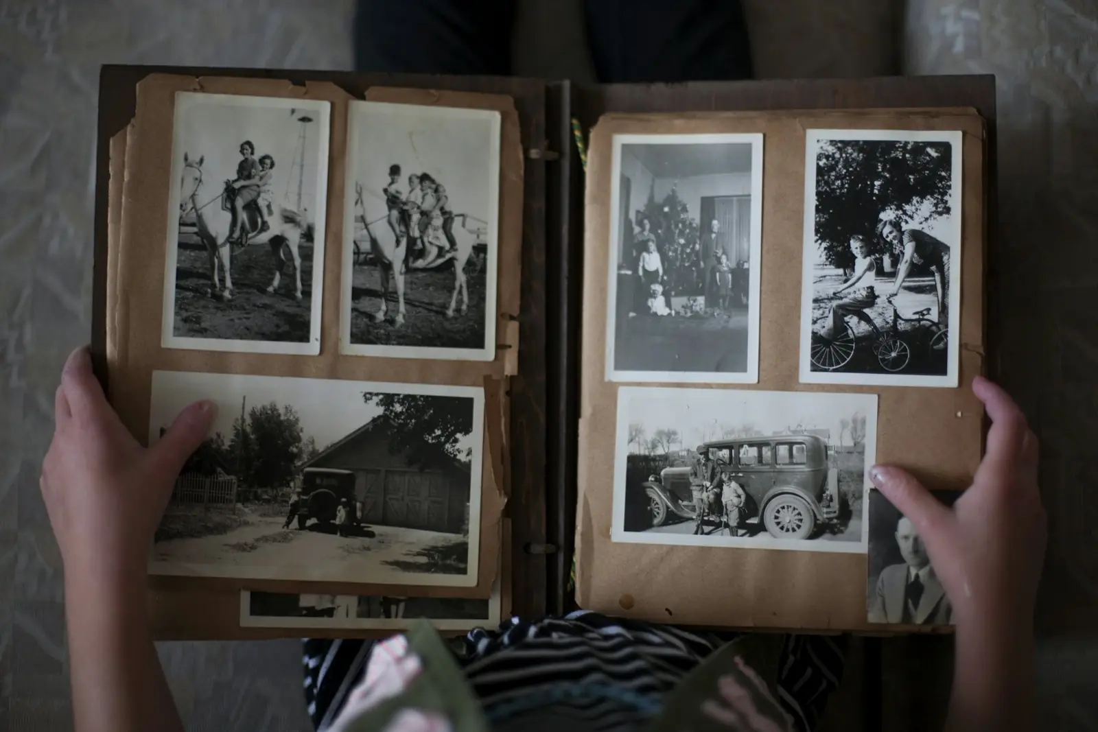 Deux mains tiennent un vieil album de photos de famille en noir et blanc